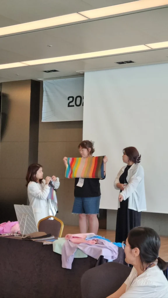 무대에서 레인보우 컬러 드레이프 원단을 펼쳐 보이는 워크숍 현장